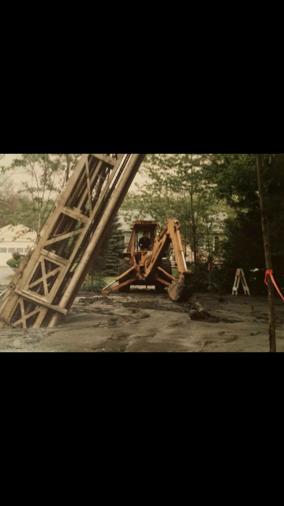 Backhoe working near a drill rig sunk into the ground in East Fishkill